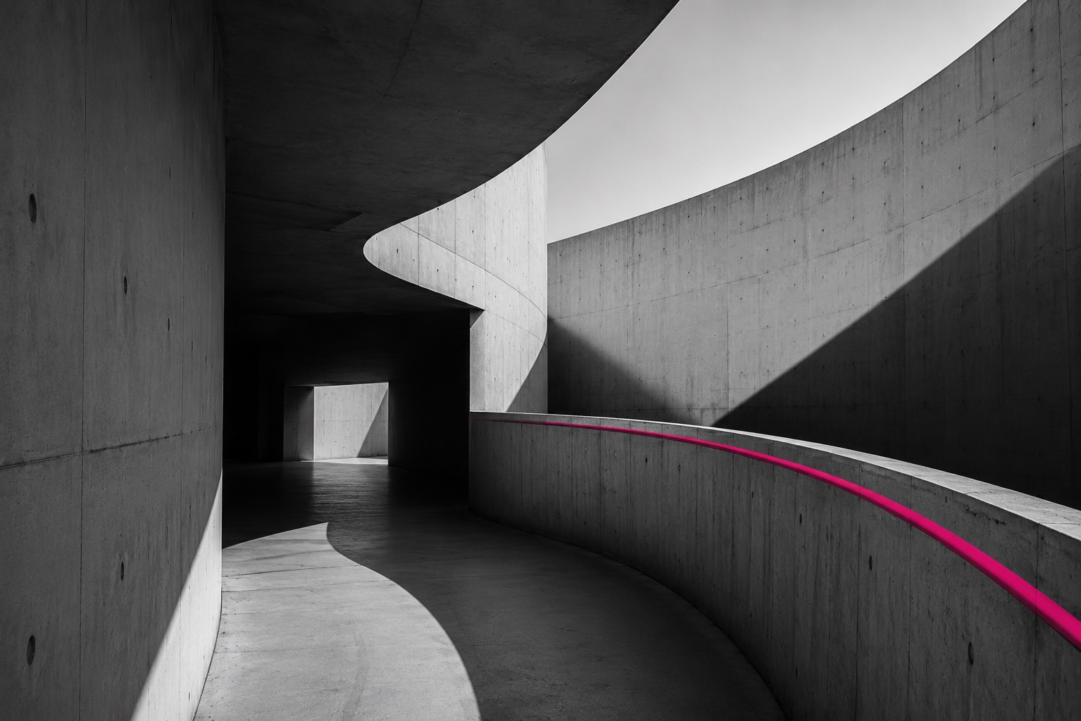Curving concrete architecture with a single magenta line following the path.